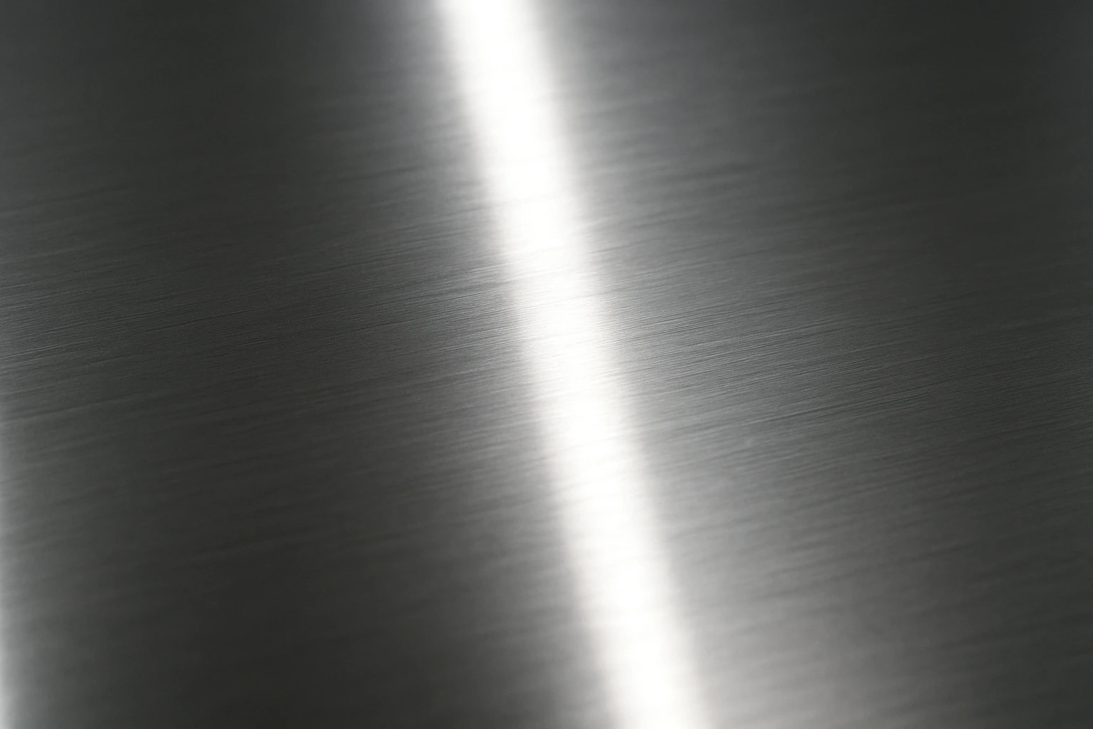 Close-up macro shot of polished stainless steel with a reflective surface under bright industrial lighting, showing smooth metallic texture for a detailed stainless steel vs carbon steel comparison.